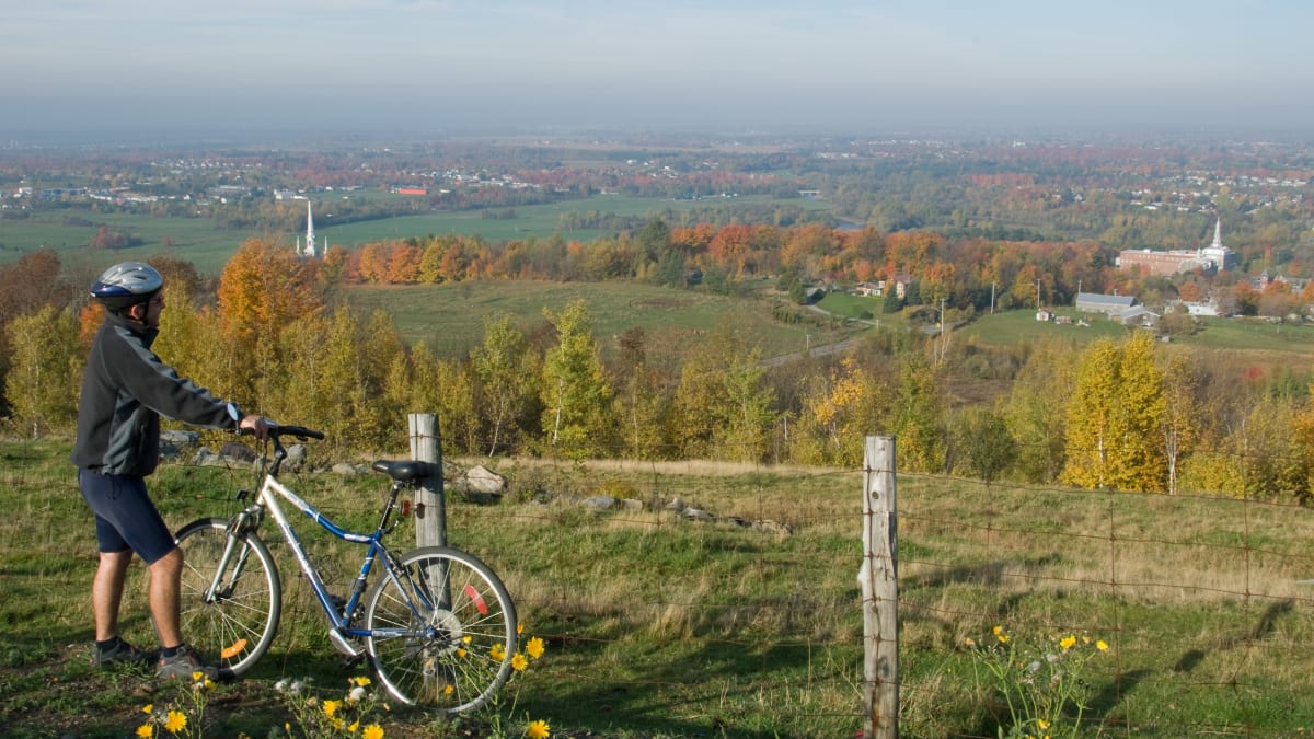 Homme avec une bicyclette qui admire la vue de Arthabaska l'automne.