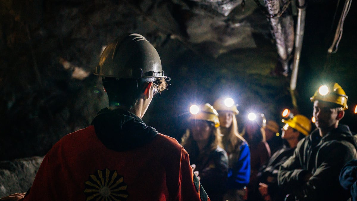 Groupe de personnes dans une mine sombre, portant des casques de protection