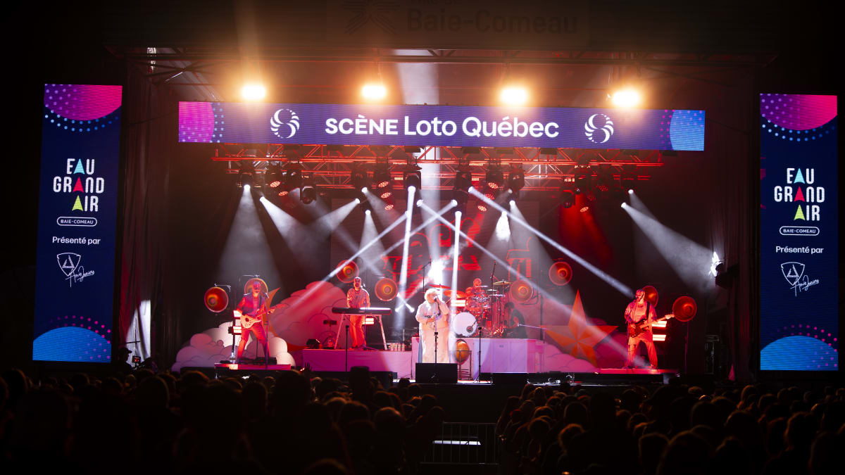 Scène illuminée du Festival Eau Grand Air en soirée.