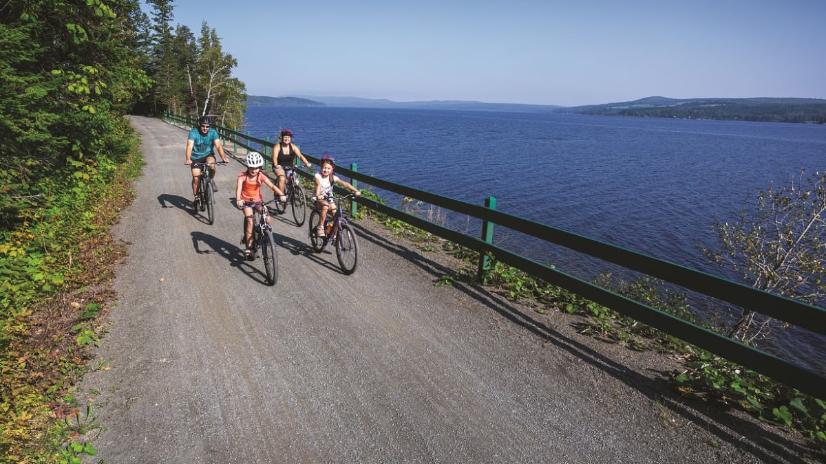 Famille de 4 personnes en vélo au bord du lac.