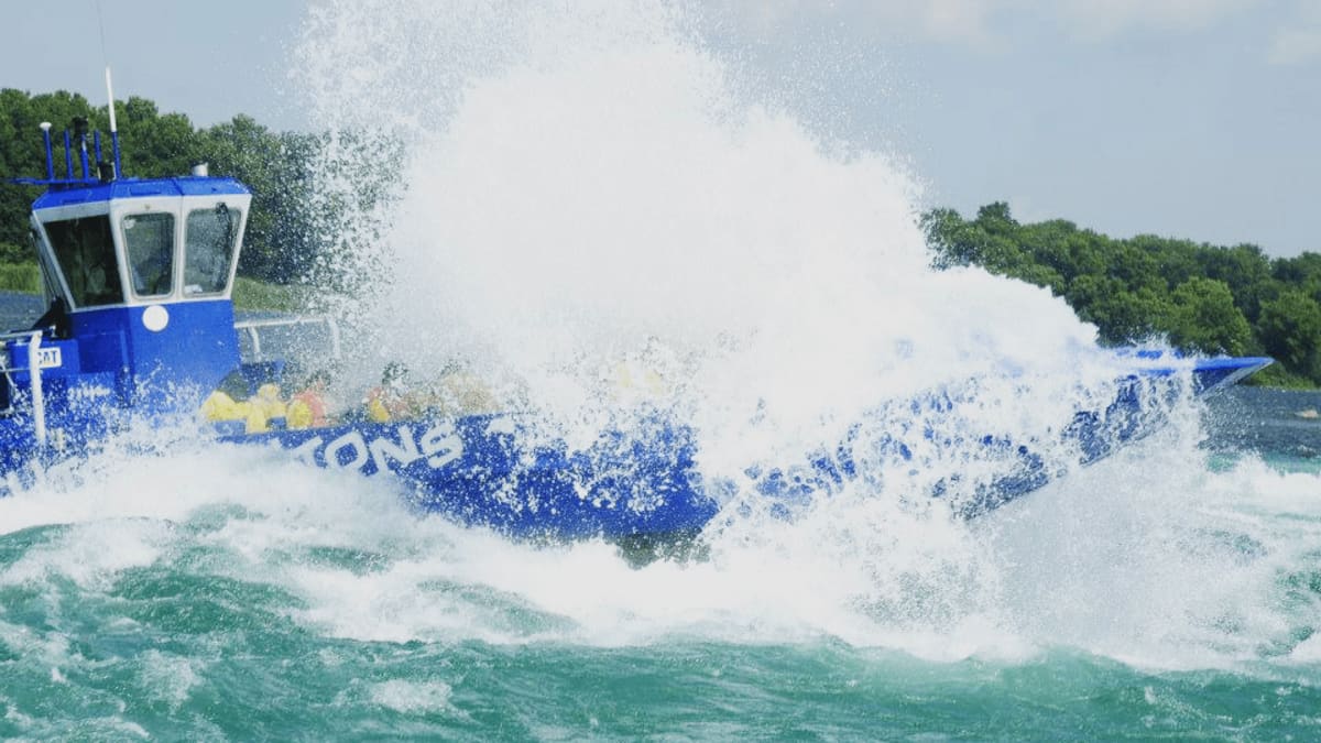 Bateau bleu Saute-Moutons entouré d'éclaboussure alors qu'il traverse une vague.