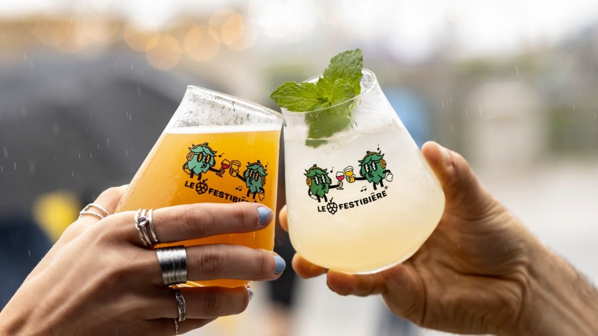 Gros plan de deux mains tenant des verres de bières à l'effigie du Festibière.