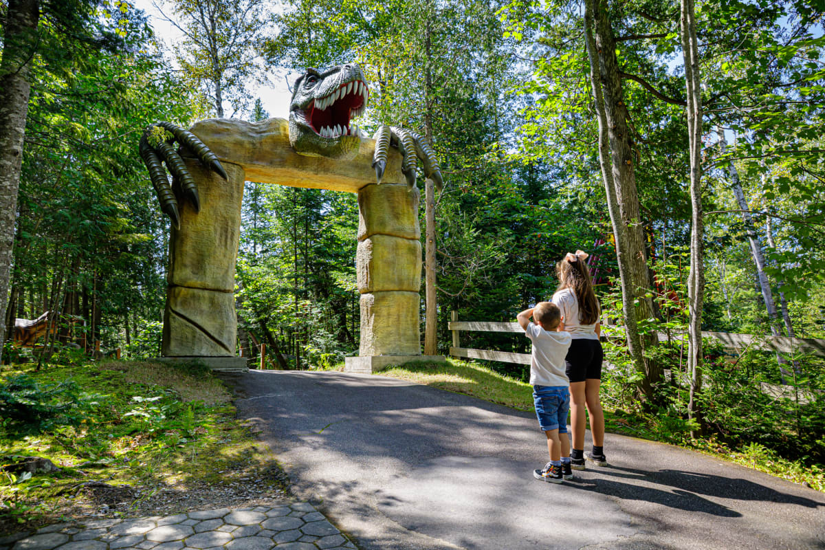 Deux enfants devant une porte surmontée d'une tête de dinosaure