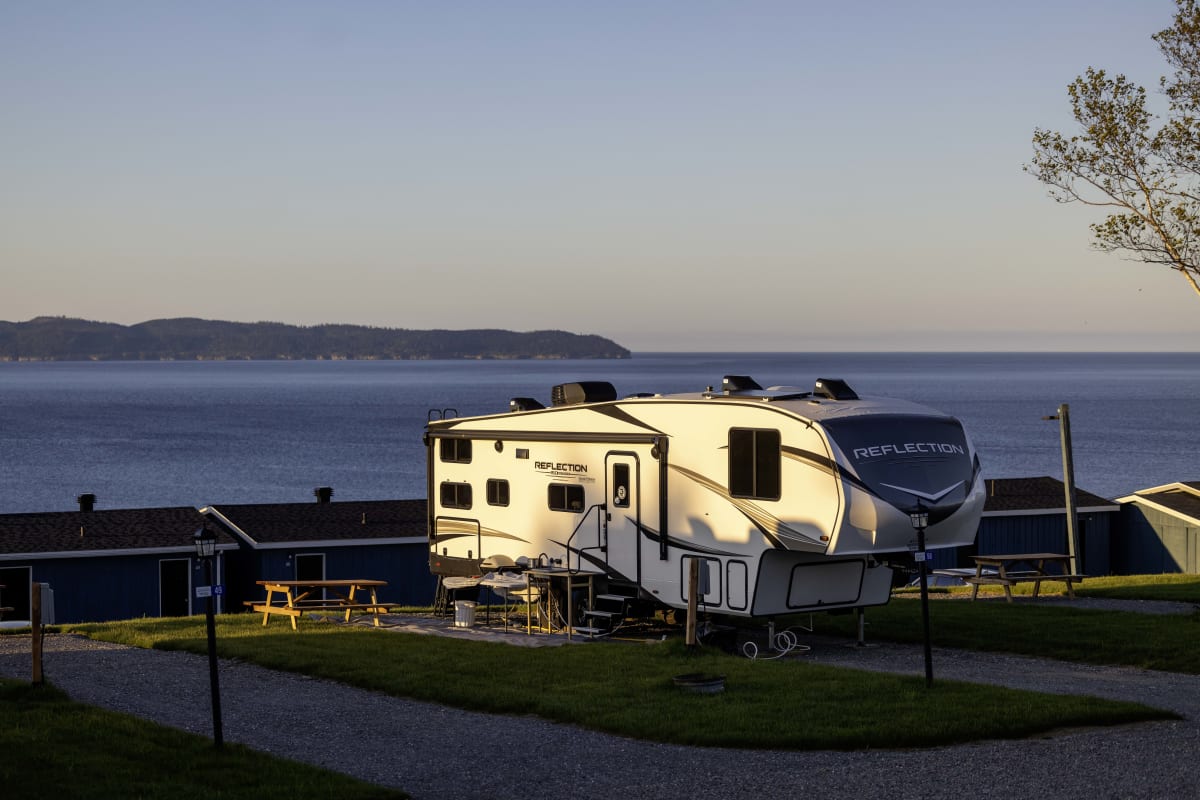Roulotte installée sur un terrain de camping avec vue sur l'eau.