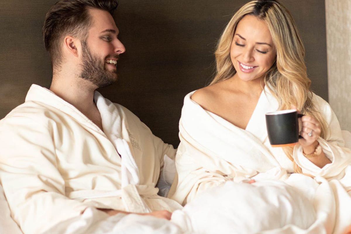 Couple relaxant au lit en peignoirs avec une tasse de café.
