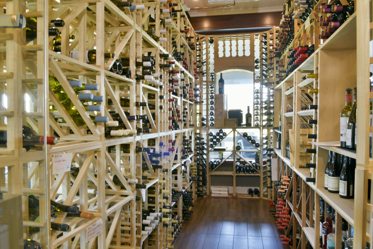 Intérieur d'un cellier bien éclairé avec de nombreuses bouteilles de vin.