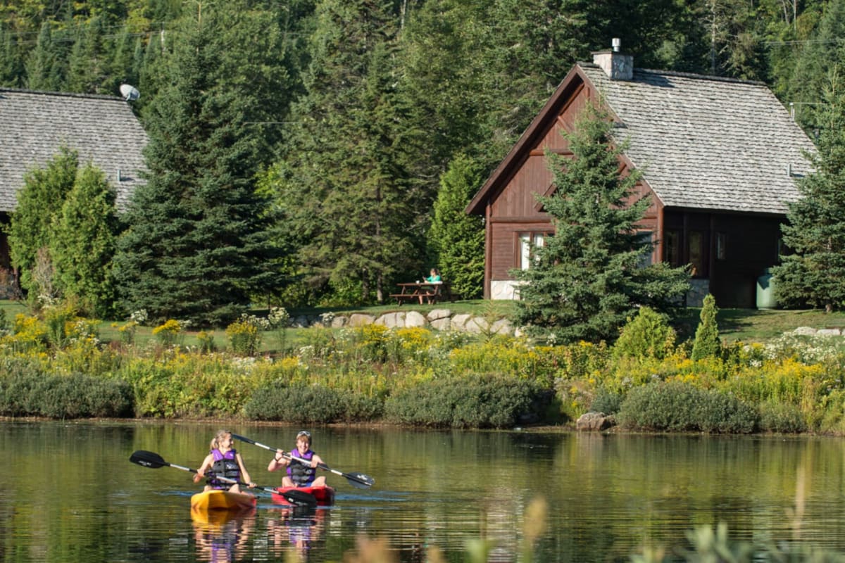 Deux personnes en kayak sur un plan d'eau devant un des Chalets Royal Laurentien.