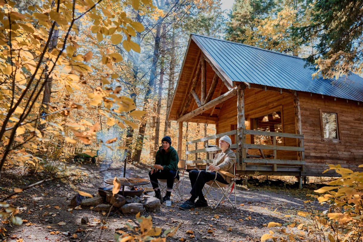 Couple devant un chalet Huttopia Sutton en automne