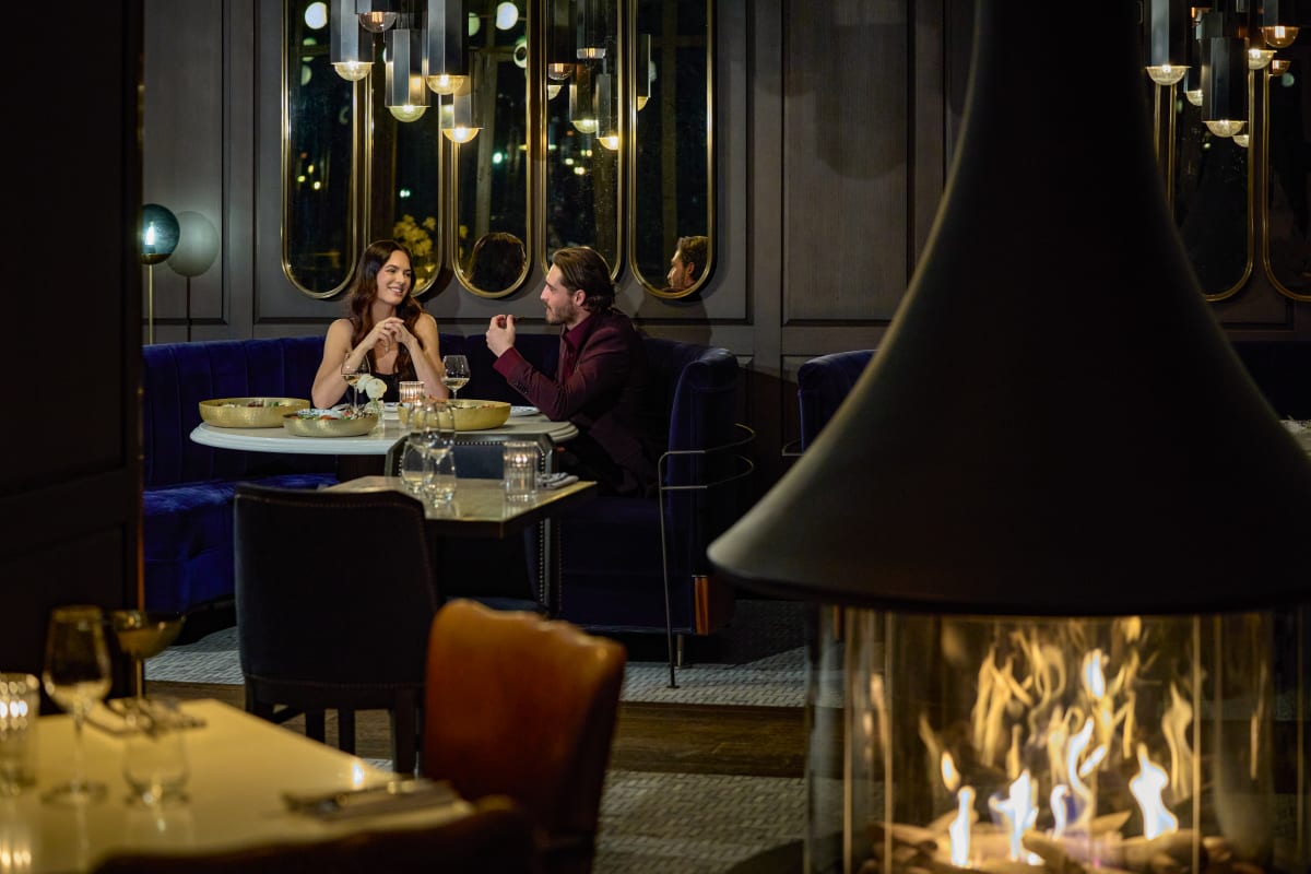 Couple dans un restaurant du Fairmont Tremblant, avec un foyer en avant-plan