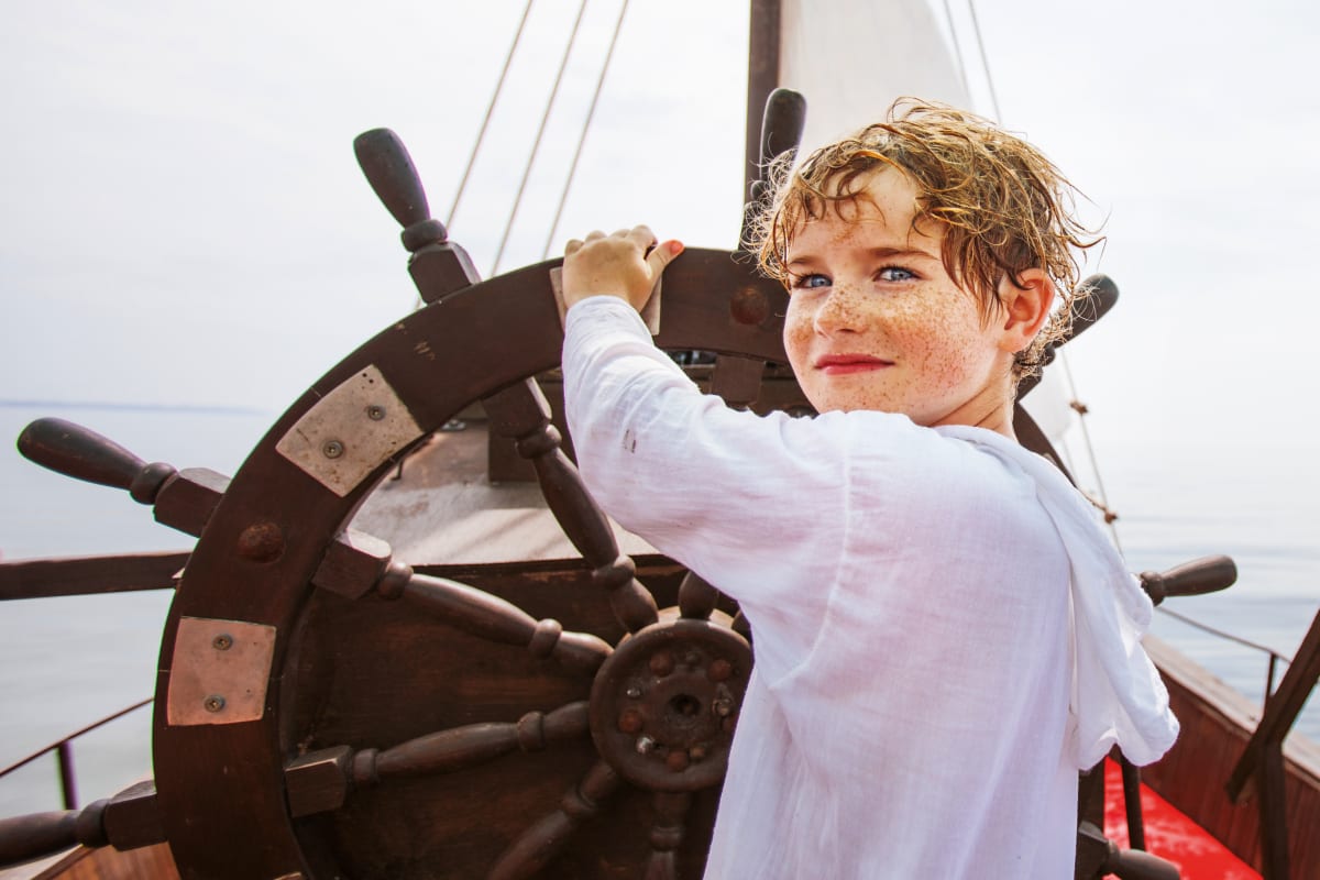 Garçon au gouvernail d'un bateau.