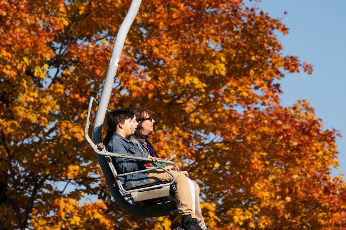 Two adults on a ski lift at Ski Saint-Bruno in the fall.Fall foliage galore!