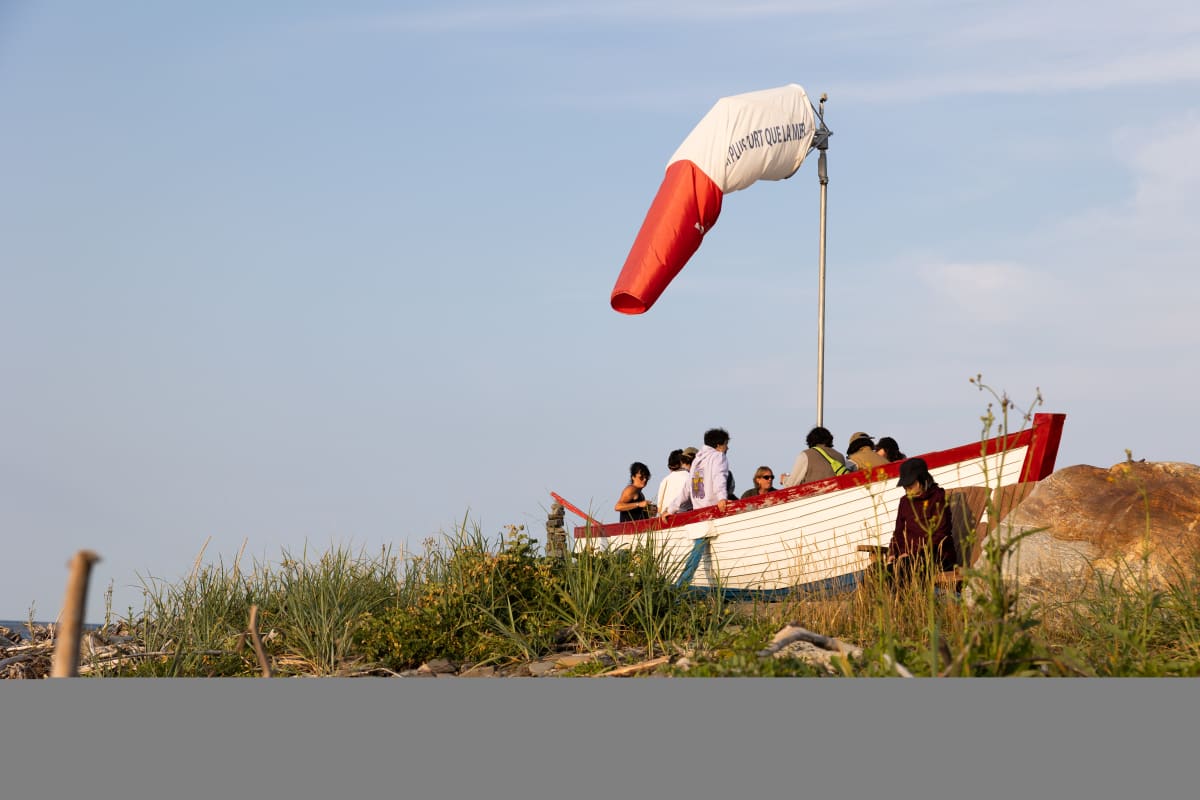Groupe dans un bateau aménagé comme terrasse sur la rive au Festival en chanson de Petite-Vallée.