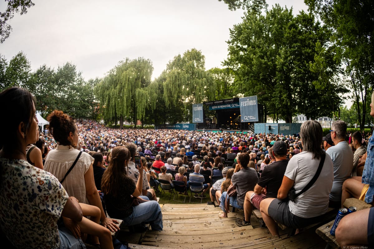 Une foule assise regarde une scène extérieure au FestiVoix de Trois-Rivières.