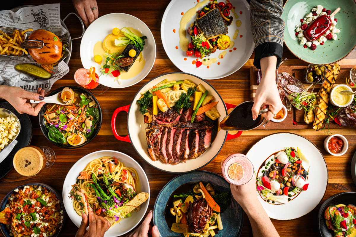 Grande table remplie de plats variés colorés et gastronomiques, vue du dessus.