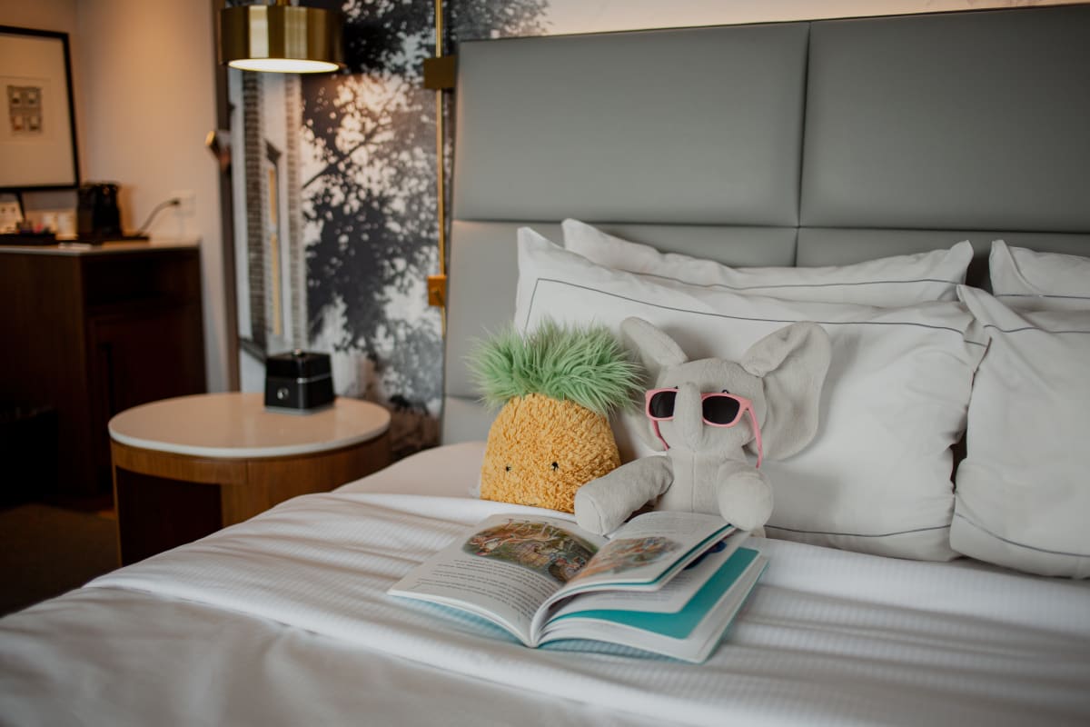 Des peluches sur un lit d’hôtel du Hilton Québec avec un livre pour enfants.
