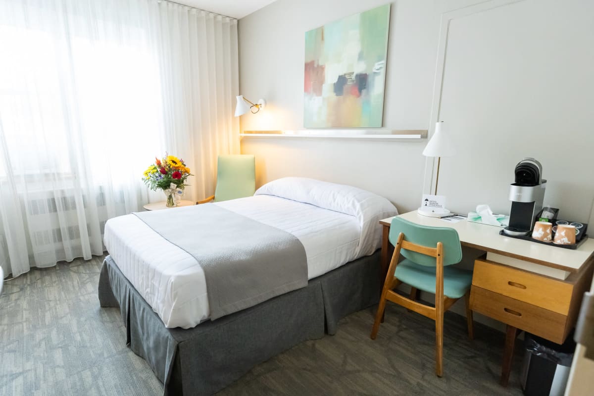 Bright guest room at Hôtel Manoir d’Youville with a bed and work desk.