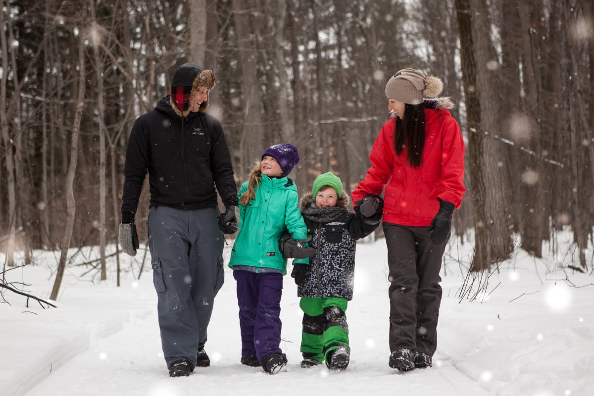 Famille marchant dans un sentier enneigé en forêt.