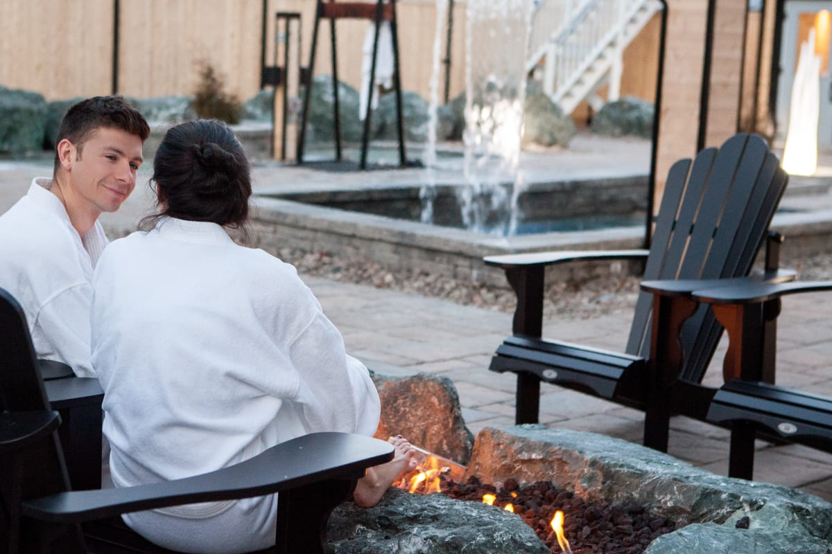 2 personnes relaxant près d'un feu à l'extérieur au spa. 