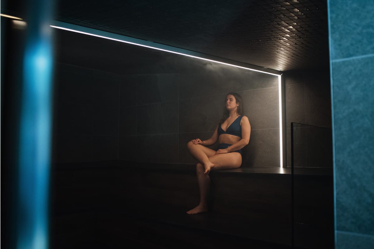 Femme en train de relaxer dans une salle de sauna sombre.