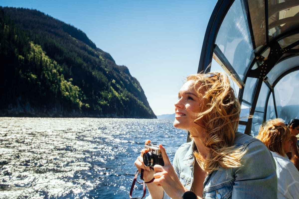 Les navettes maritimes du Fjord - Une femme sur un bateau tient une caméra.