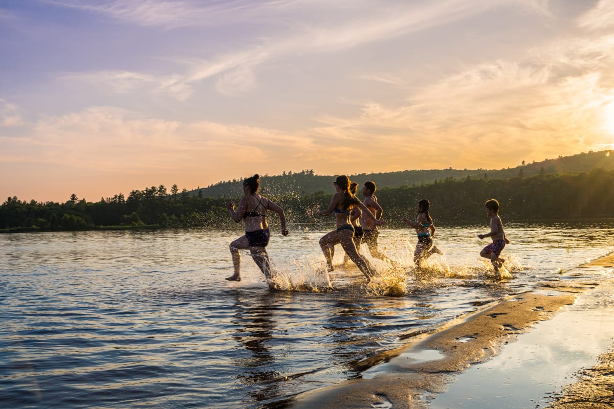 Groupe d'ami·es qui court se baigner dans le lac.