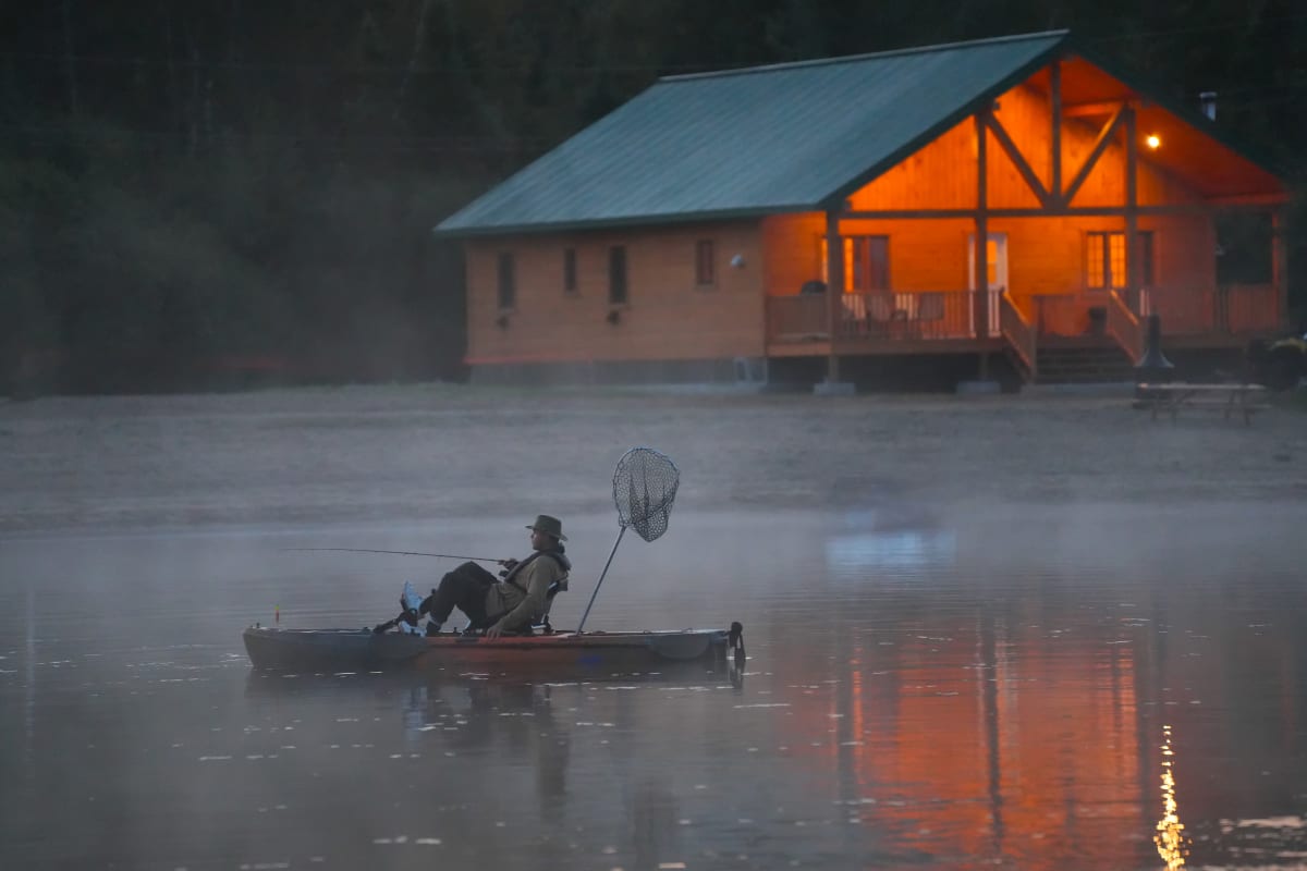 Personne sur un ponton sur le lac devant un chalet.