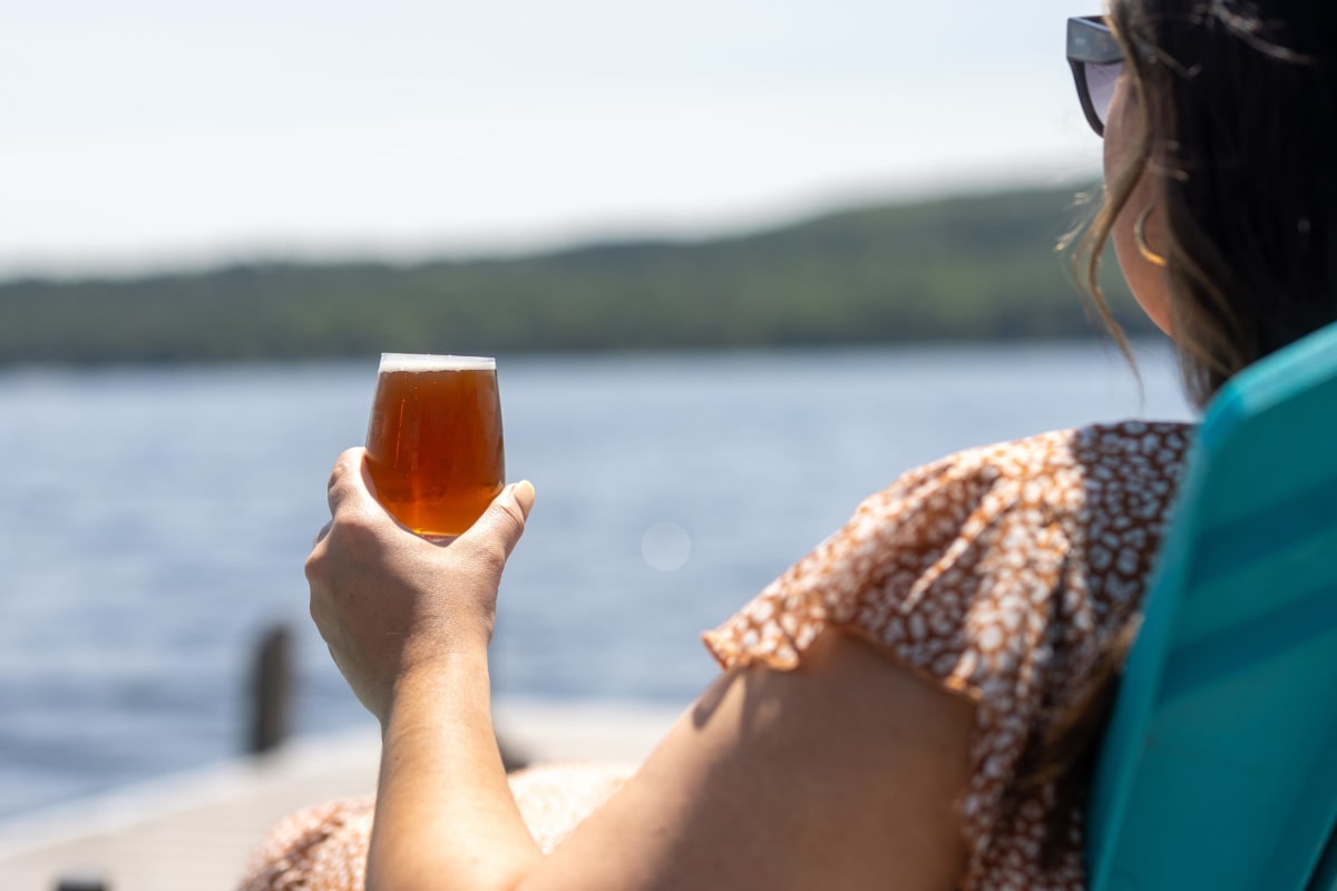 Woman with a beer by the lake.