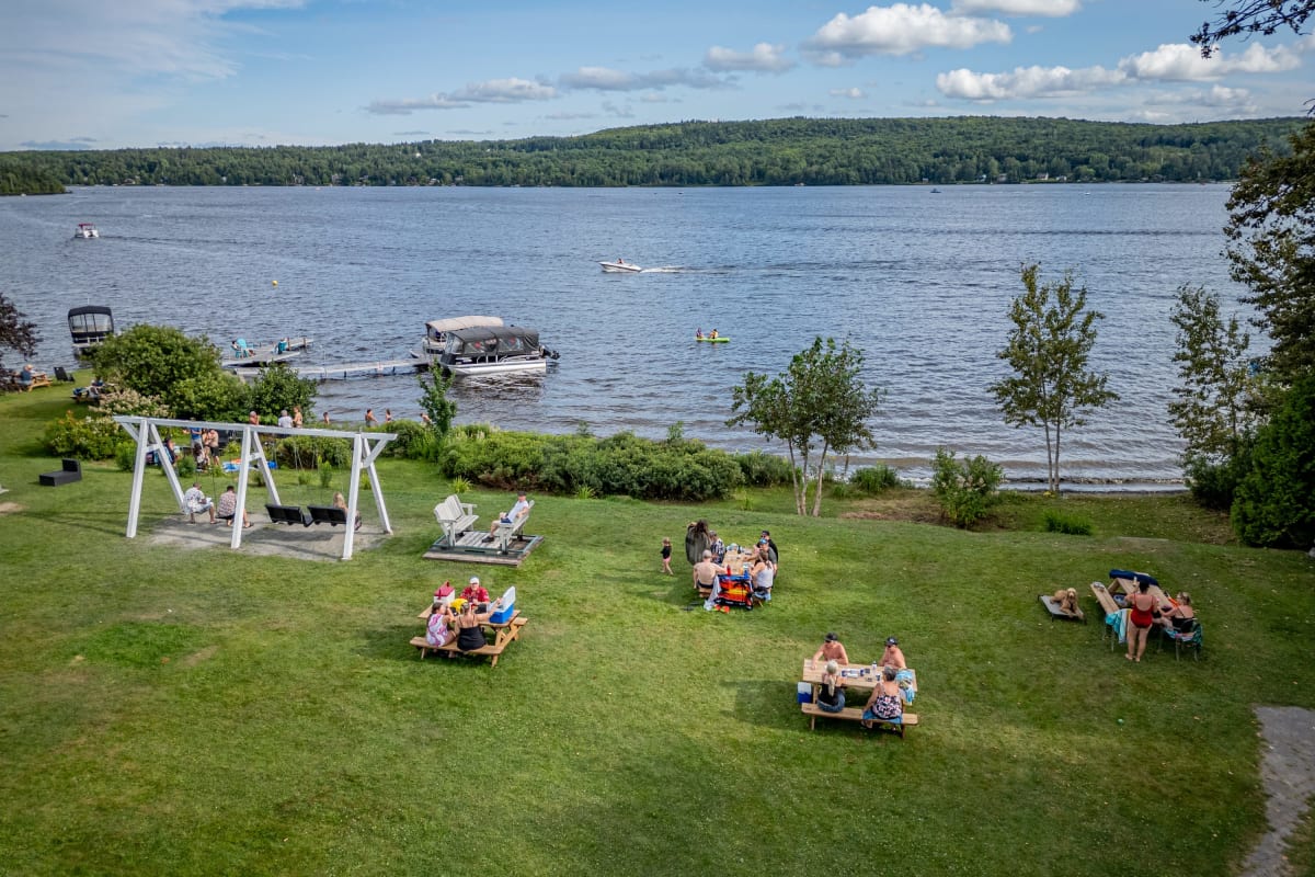 Groups of people sitting by the water at Manoir Lac-Etchemin.