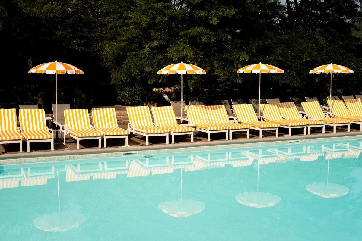 Chaises longues et parasols au bord de la piscine au Sun Club du Manoir Saint-Sauveur.