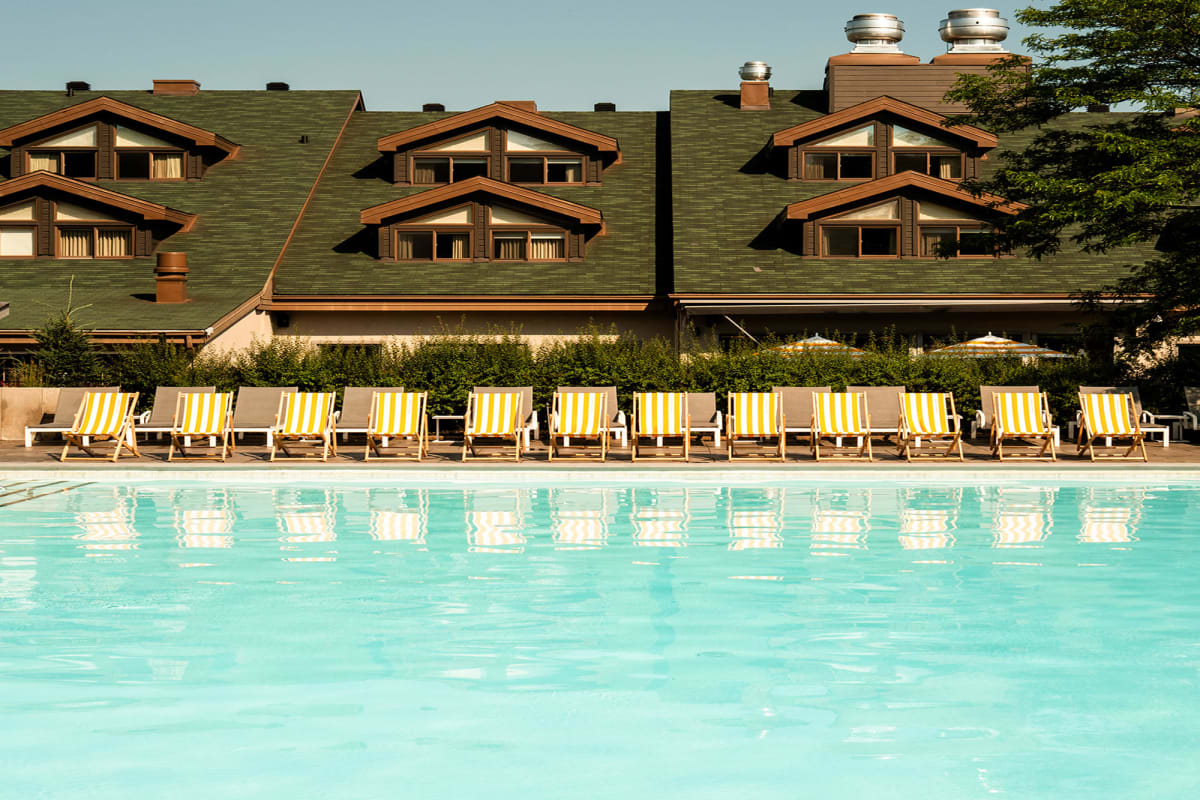 Chaises longues et parasols au bord de la piscine au Sun Club du Manoir Saint-Sauveur.