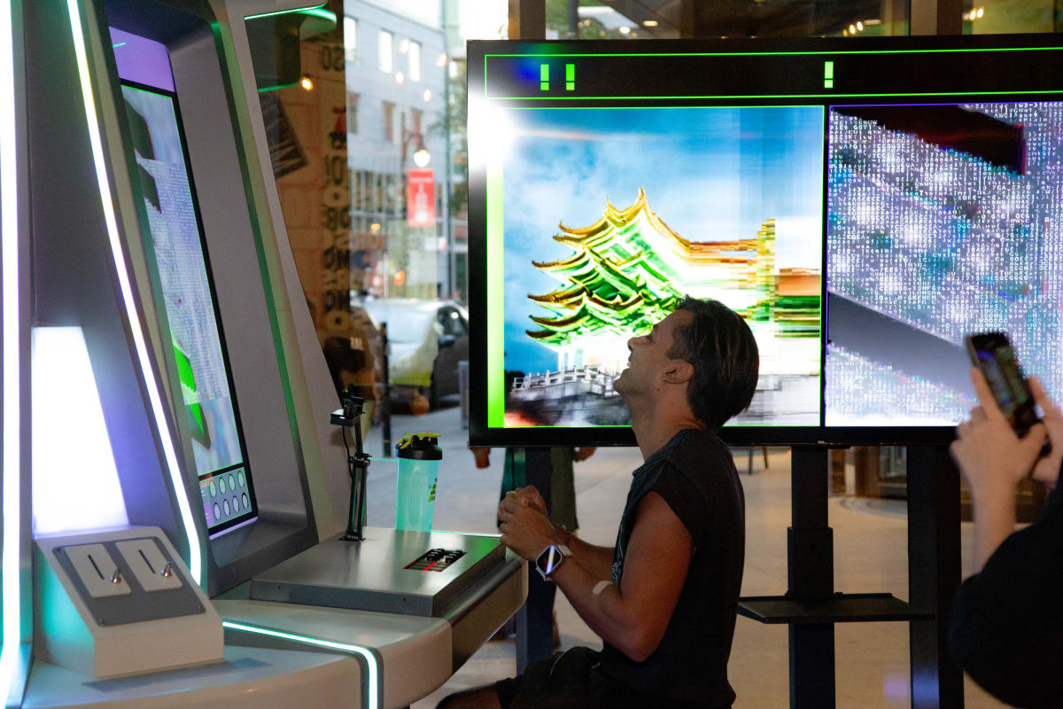 A man standing in front of a Dimension Plus screen, playing AI Street Fighting