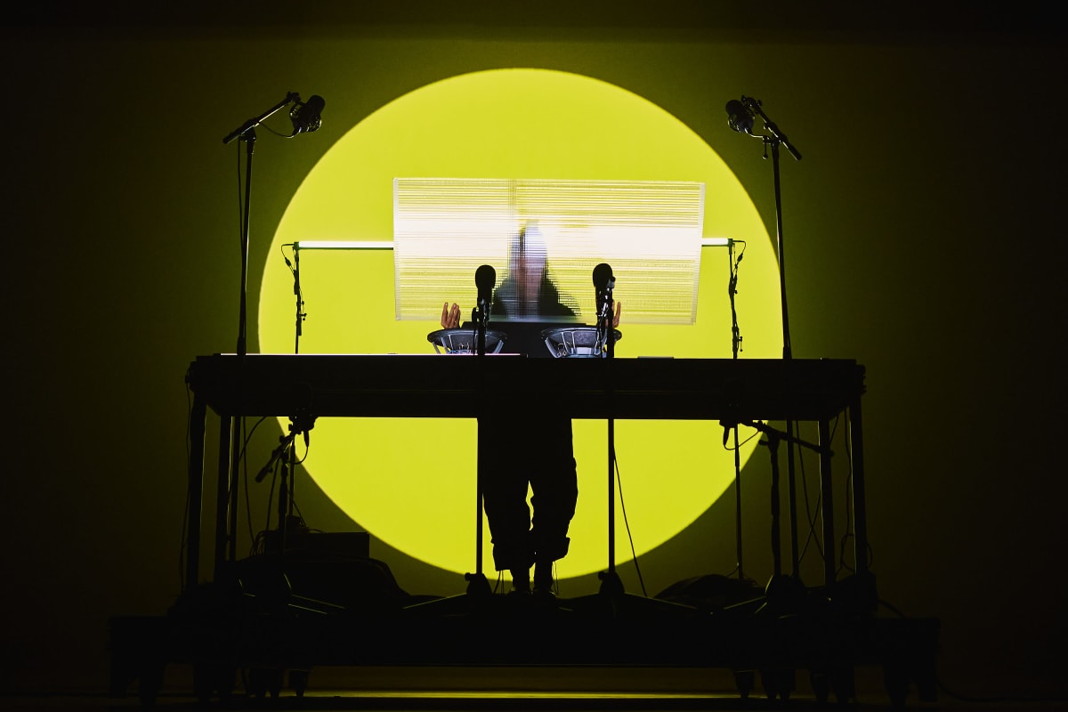A DJ on stage, behind his turntable, with a round, sun-yellow backlight at the MUTEK festival