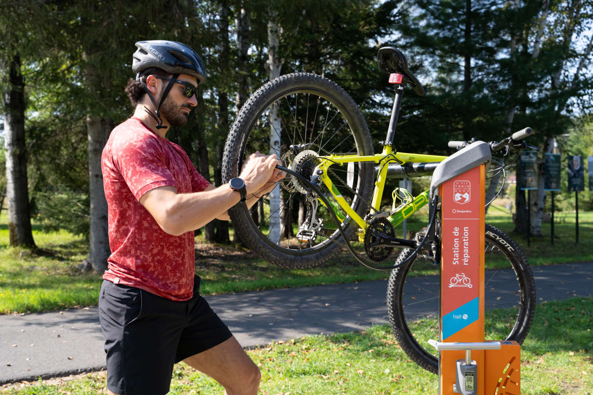 Cyclistes qui répare son vélo sur le parc linéaire du P'tit train du Nord.