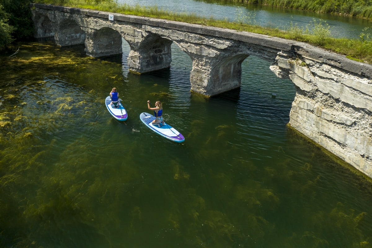 Deux personnes font de la planche à pagaie au Parc régional du canal de Soulanges.