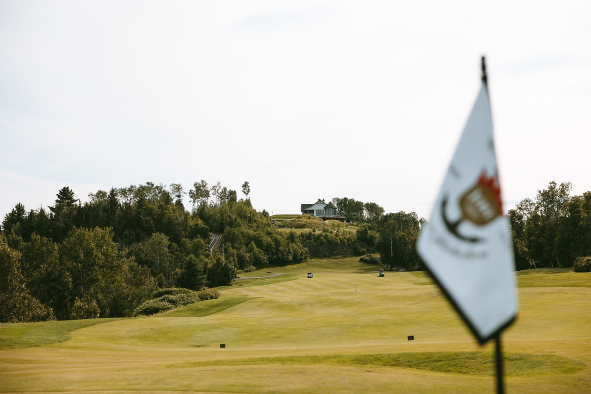 Vue rapprochée d'un drapeau, avec une parcours de golf en arrière-plan.
