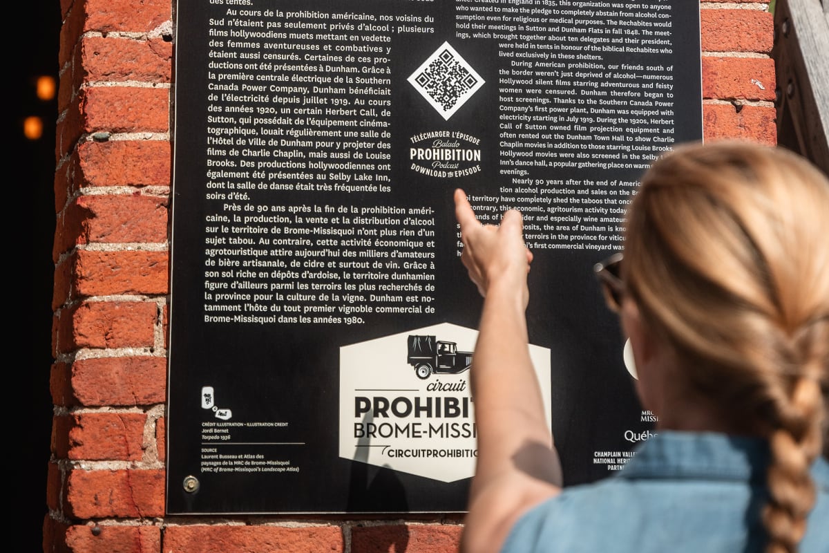 Femme qui lit un panneau sur la route de la Prohibition dans Brome-Missisquoi.