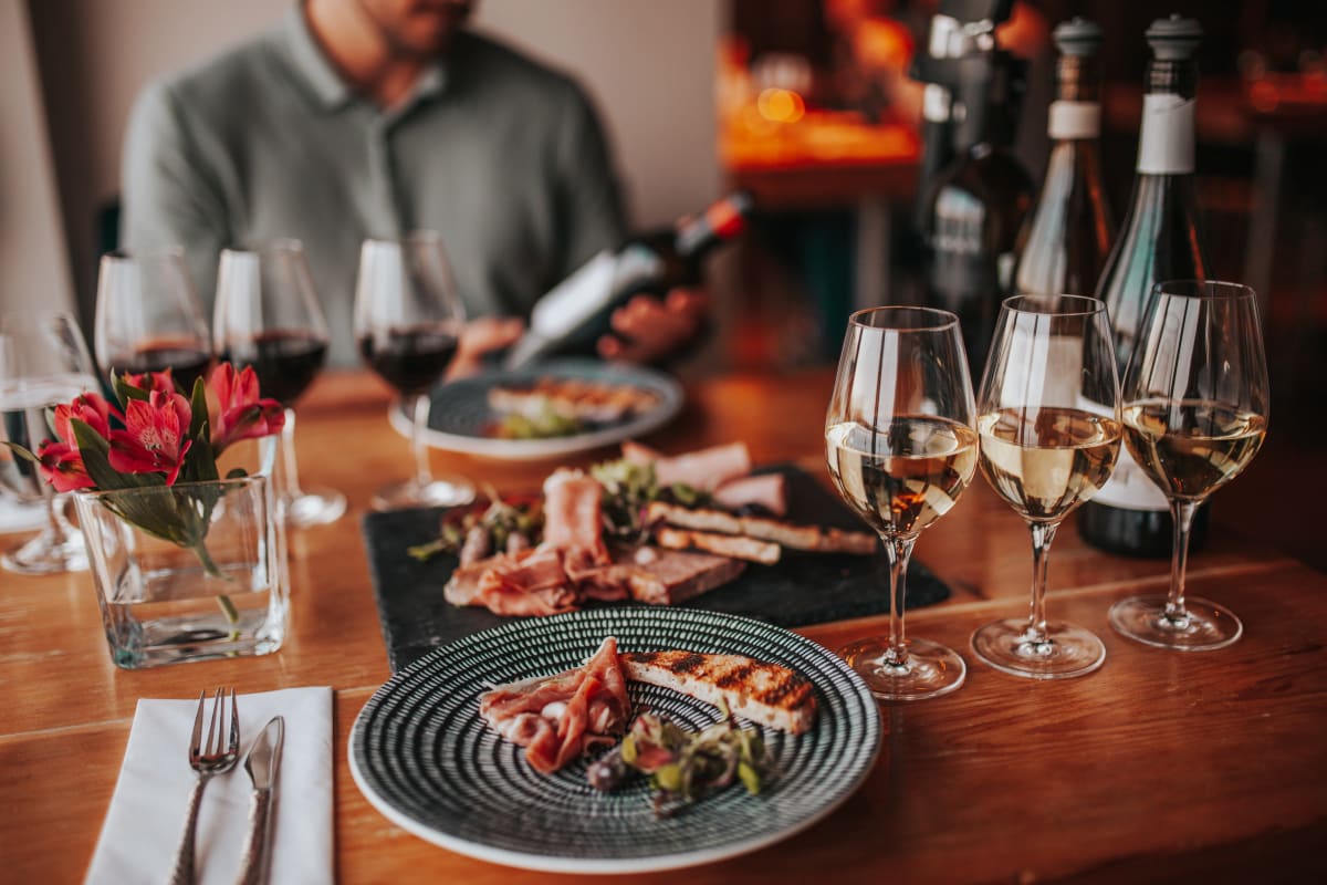 Table de dégustation avec assiette et plusieurs verres de vin.