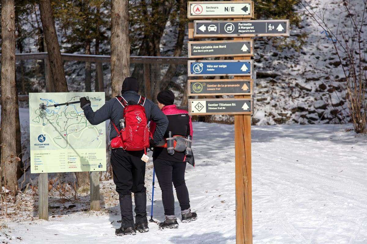 Un homme et une femme en randonnée pédestre l'hiver dans le parc de la Gorge de Coaticook.