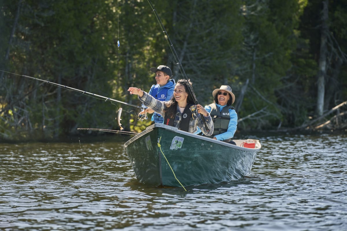 Family fishing in a forest-green fiching row.