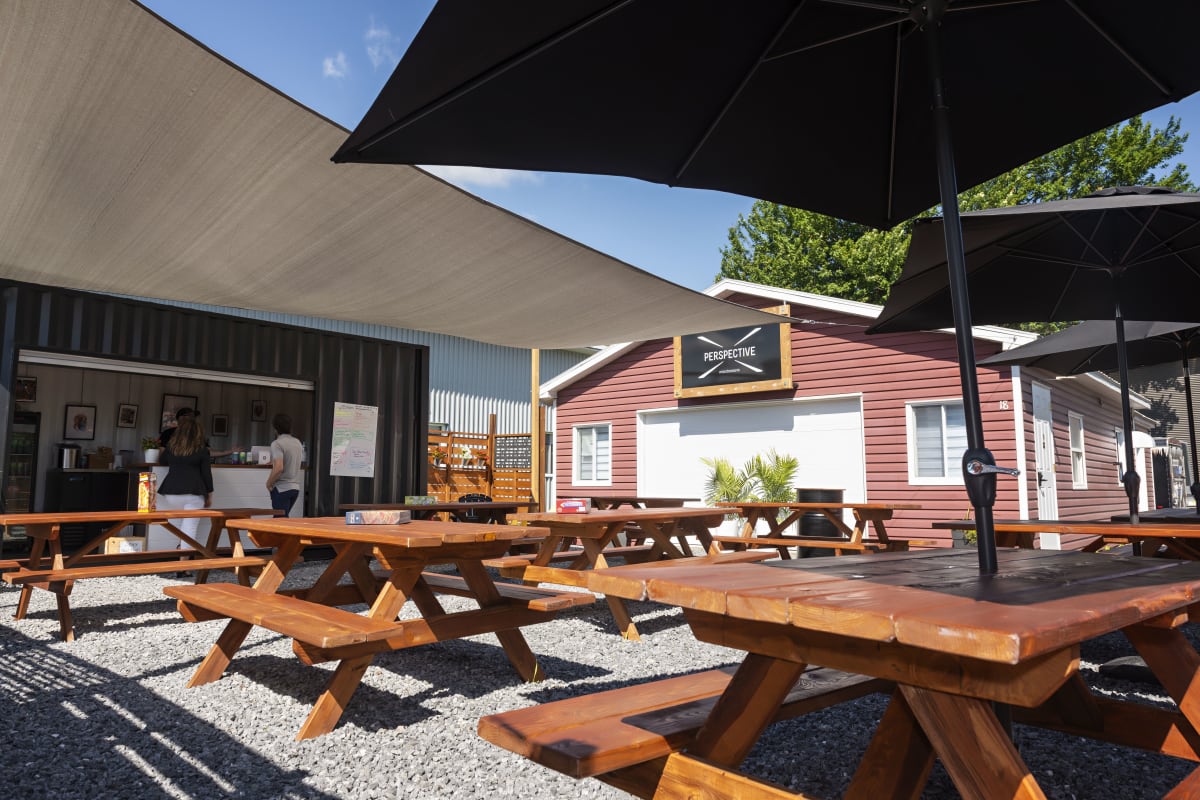 Terrasse de la microbrasserie Perspective, avec tables à pique-nique et parasols.