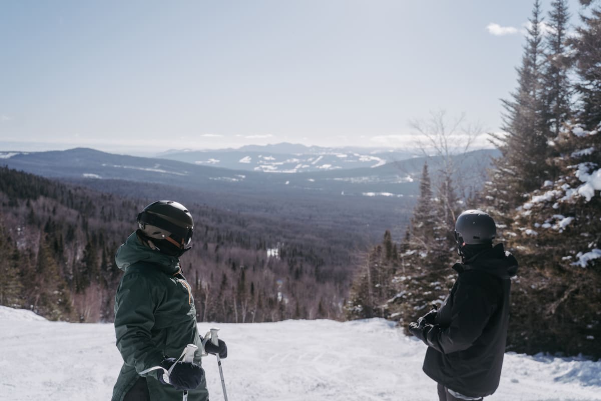 Deux personnes sur une pente de ski, en train de regarder le paysage.