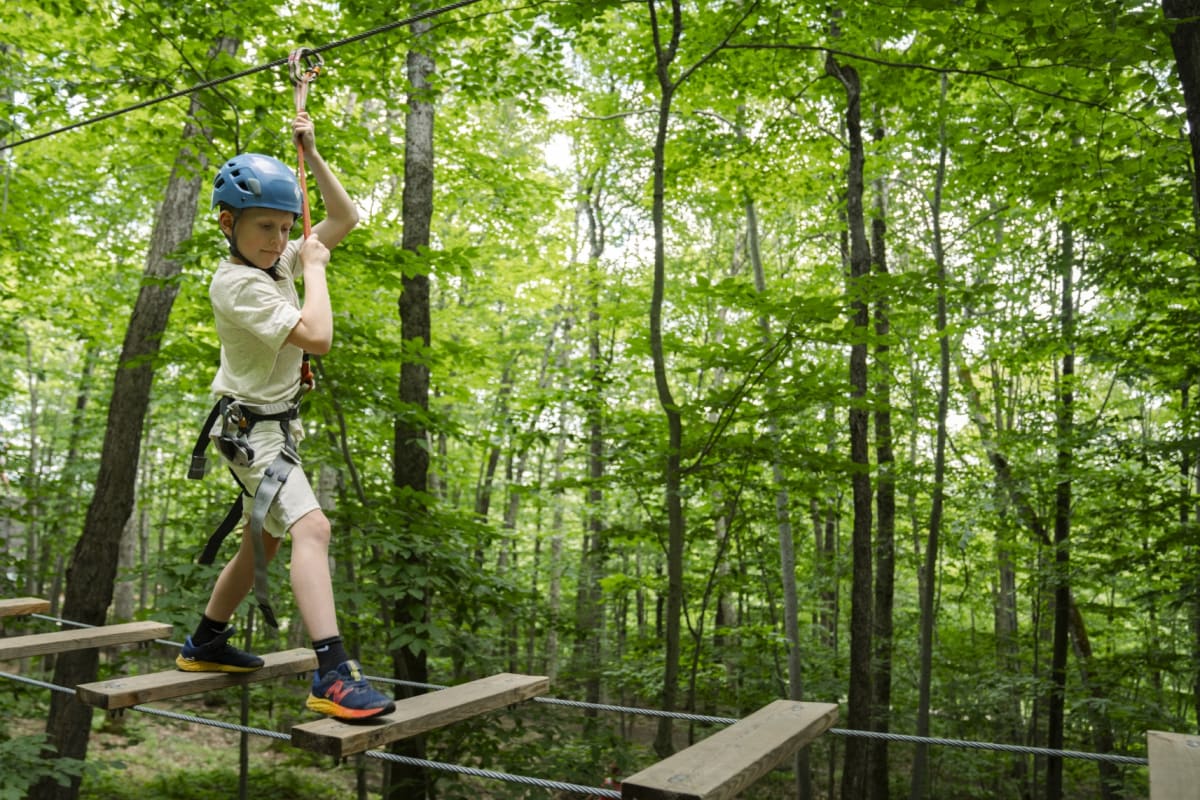 Boy on a treetop obstacle course at Station touristique Duchesnay.