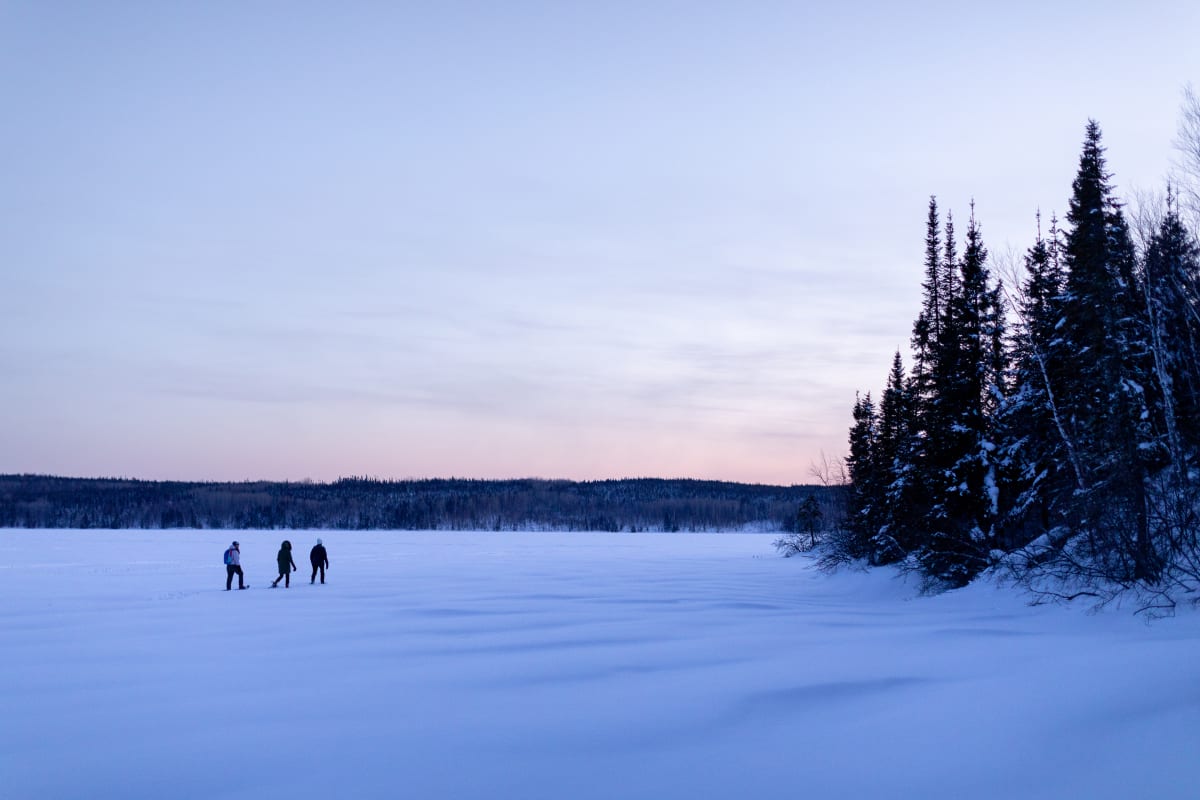 Corporation Nibiischii - Trois personnes au coeur d'un paysage enneigé