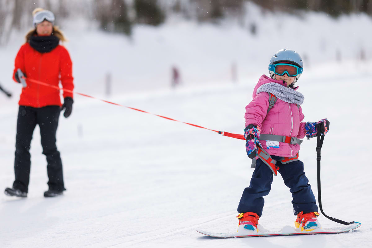 Jeune fille en train d'apprendre la planche à neige avec une monitrice.