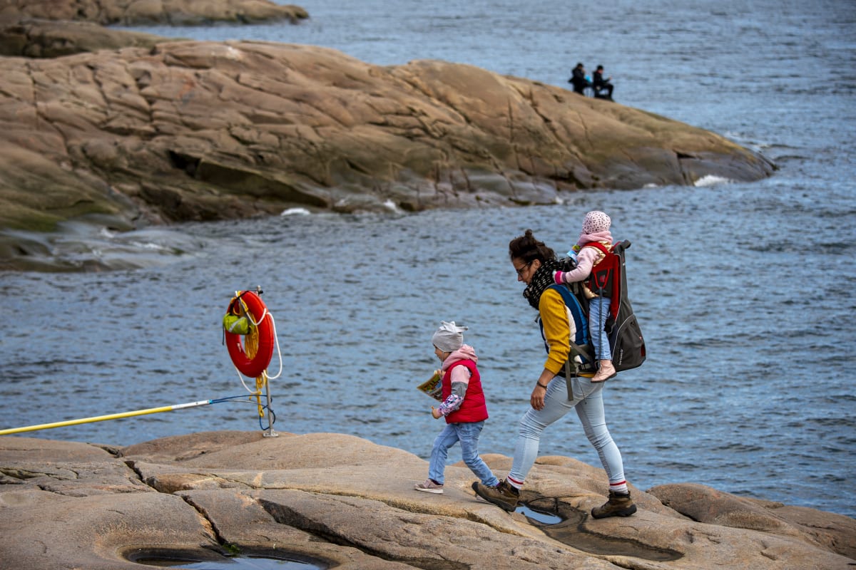 Mother and two kids walking by the sea.
