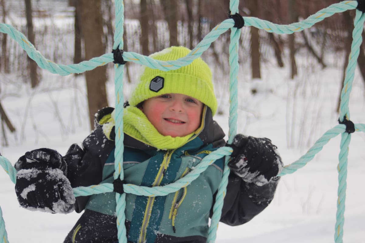 Enfant dans un module de jeux extérieur en hiver.