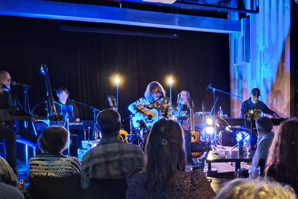 Groupe de musiciens en train de donner un spectacle dans une salle intimiste. 