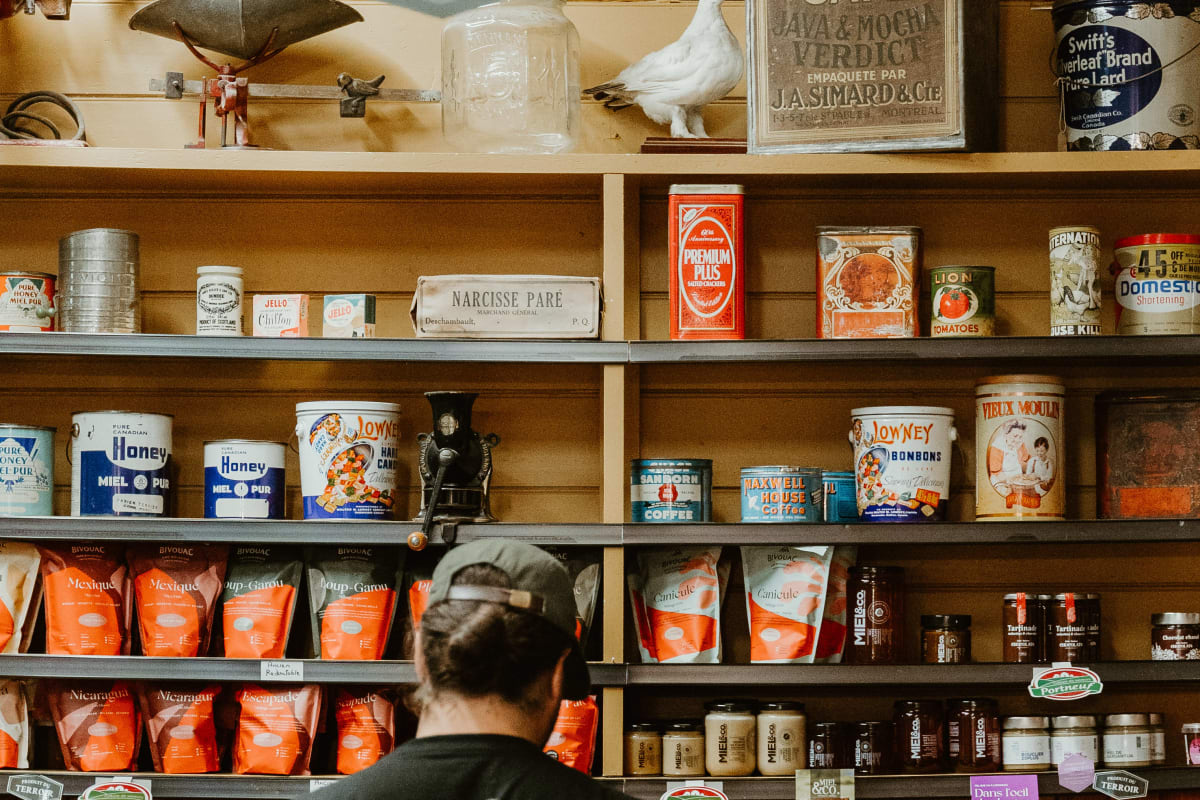 Homme devant un étalage de produits du terroir en boutique.