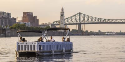 Des amis font une croisière sur le fleuve Saint-Laurent à bord d'un ponton électrique.
