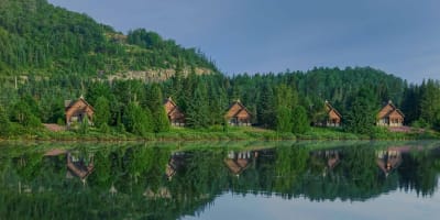 Chalets paisibles au bord d'un lac avec reflet dans l'eau.